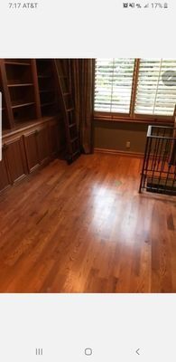 Empty wooden room with built-in shelves, polished floor, and window blinds.