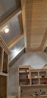 Wood-paneled room with a high slanted ceiling, skylights, and a shelf displaying small items.