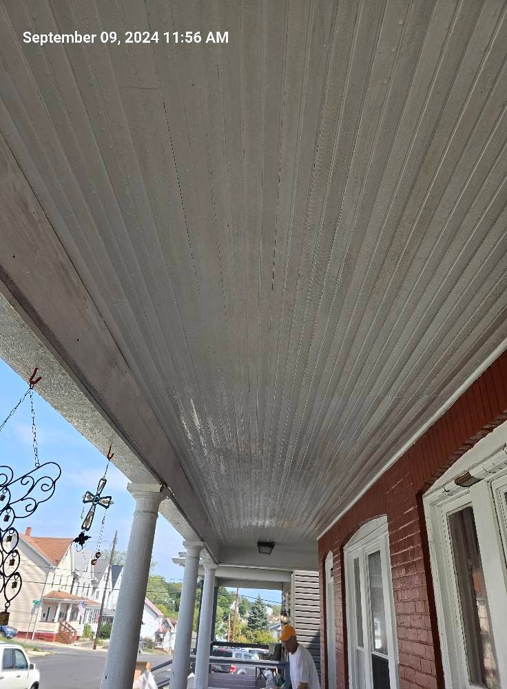 A view from a porch looking down the length of a white-paneled ceiling toward a residential street.