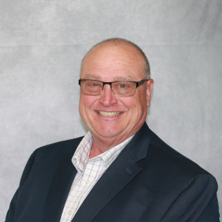 A man wearing glasses and a suit smiles for the camera