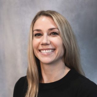 A woman with long blonde hair is smiling and wearing a black shirt.