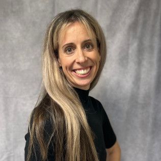 A woman with long blonde hair is smiling and wearing a black shirt.