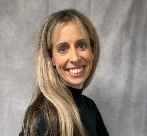 A woman with long blonde hair is smiling and wearing a black shirt.