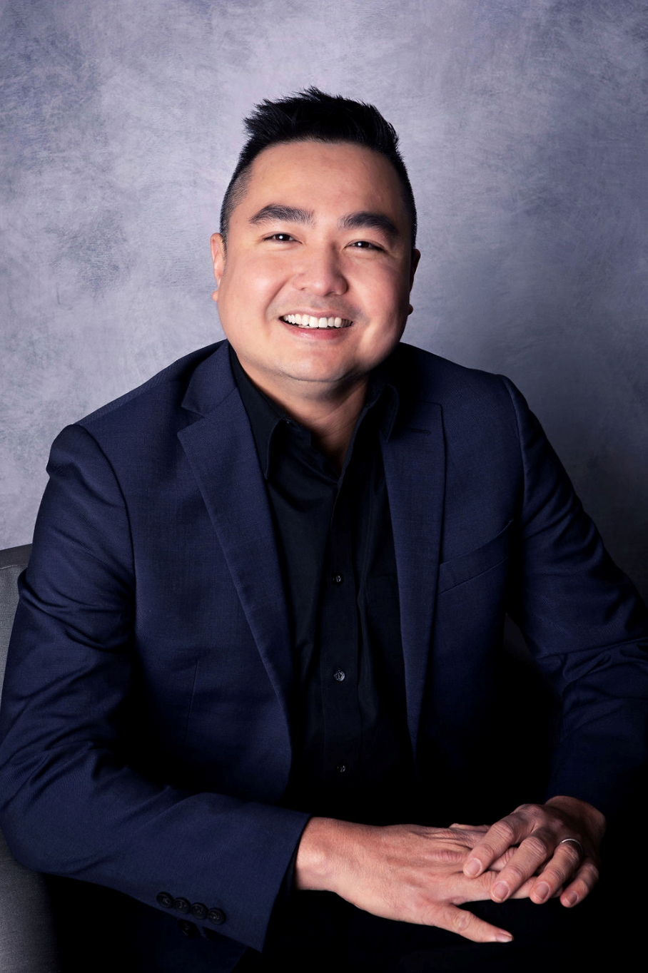 A woman wearing a headband and a necklace is smiling for the camera.