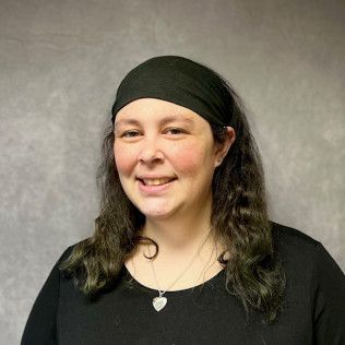 A woman wearing a headband and a necklace is smiling for the camera.