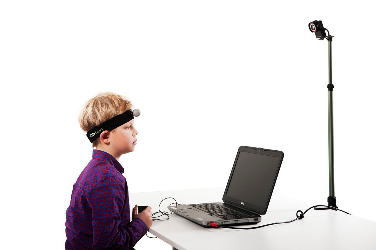 A young boy wearing a headband is sitting in front of a laptop computer.