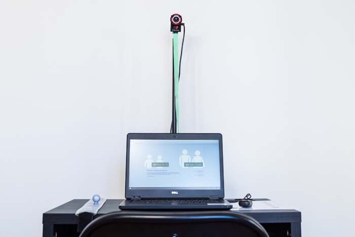 A laptop computer is sitting on a desk next to a webcam.