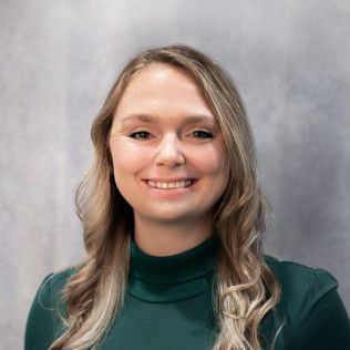 A woman in a green turtleneck is smiling for the camera.