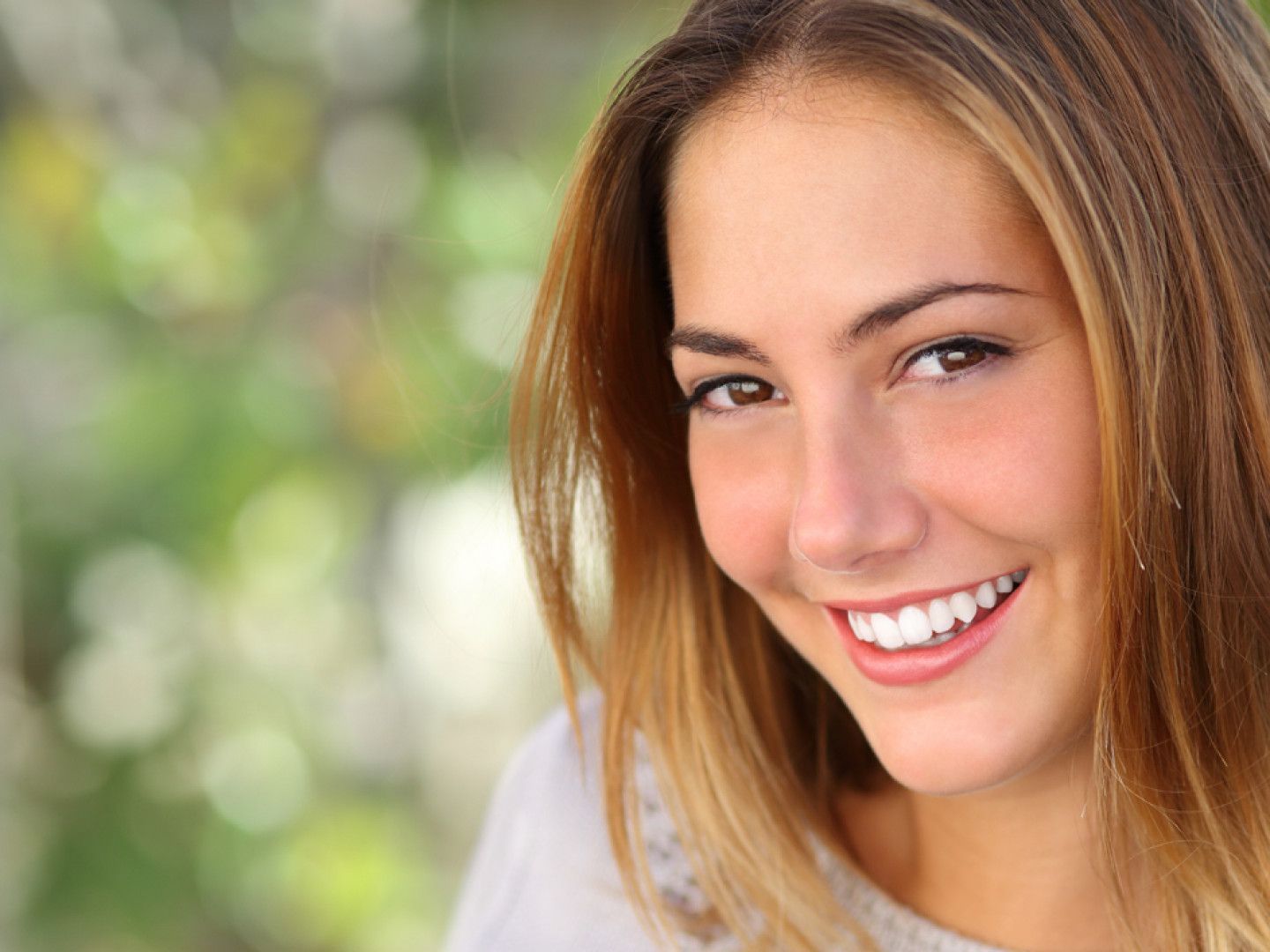 A woman with white teeth is smiling for the camera.