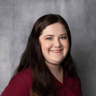 A woman in a red shirt is smiling for the camera.