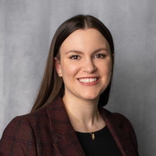 A woman wearing a plaid jacket and a black shirt is smiling for the camera.