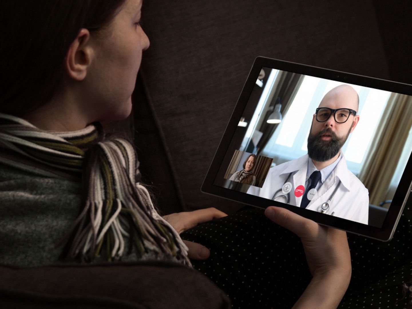 A woman is talking to a doctor on a tablet.