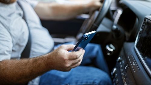 A man is using a cell phone while driving a car.