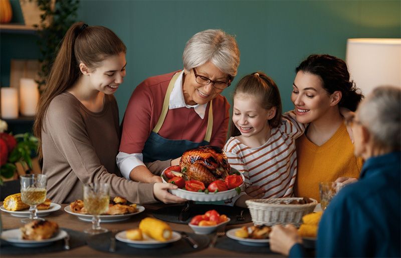 A family is sitting at a table eating a turkey.