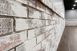 Whitewashed brick wall with a wooden floor, creating a rustic interior design.