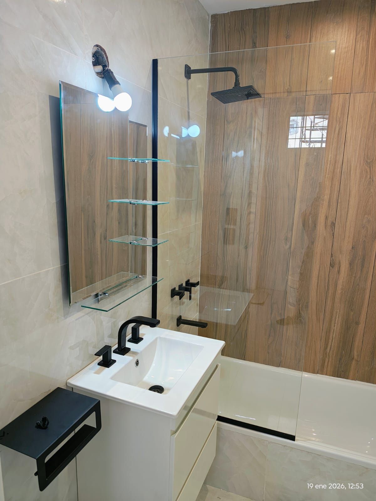 Baño moderno con bañera blanca, ducha de cristal y tocador flotante.