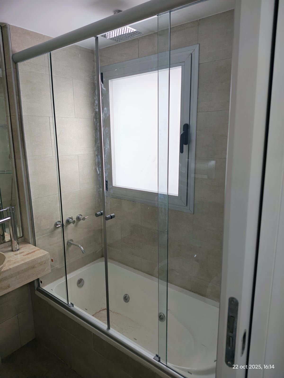 Baño moderno con pared con estampados marrones y dorados, bañera y ducha.