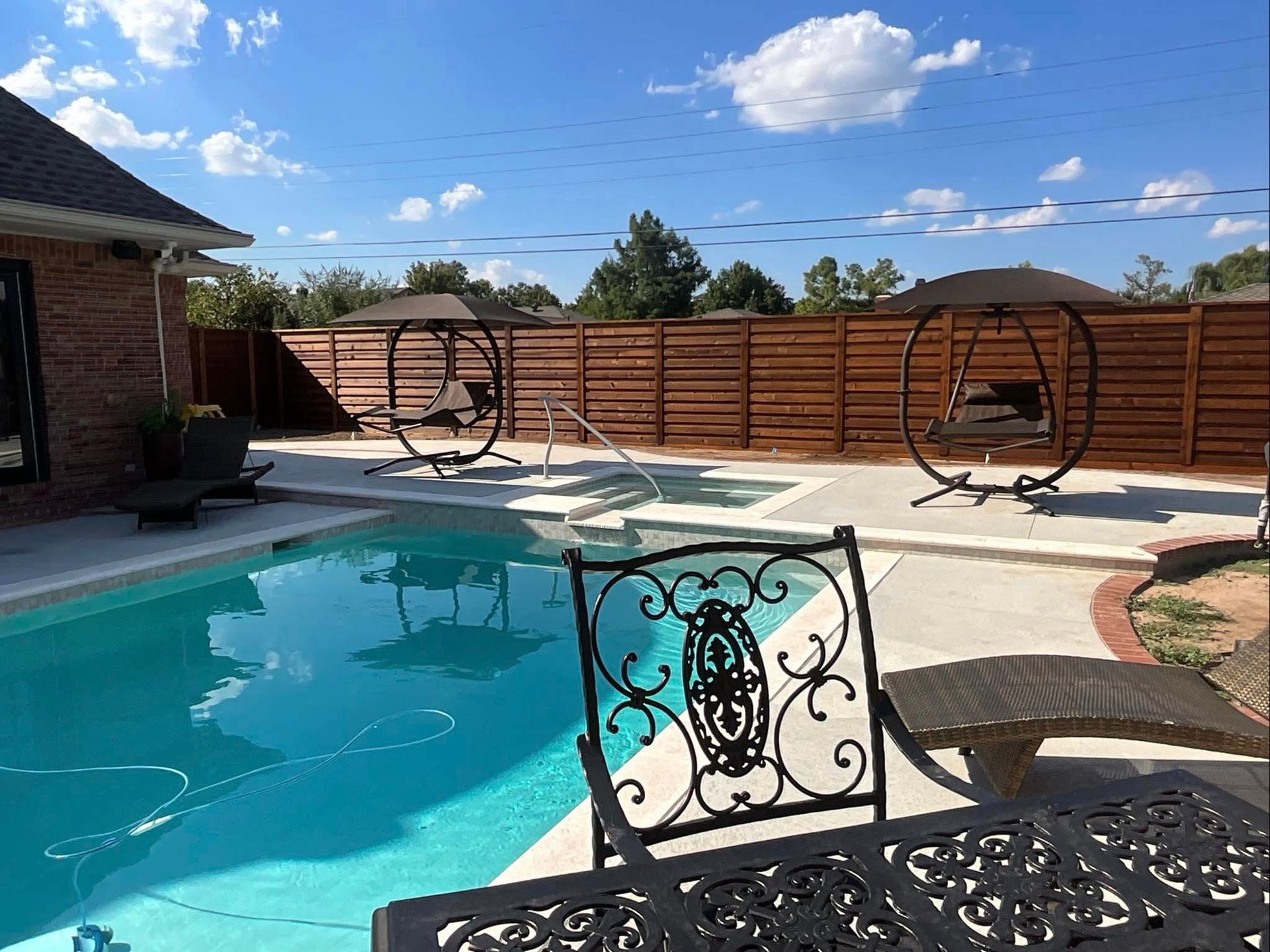 Luxury backyard pool enclosed by a cedar horizontal-slat privacy fence — a completed Legacy Fence project in Oklahoma