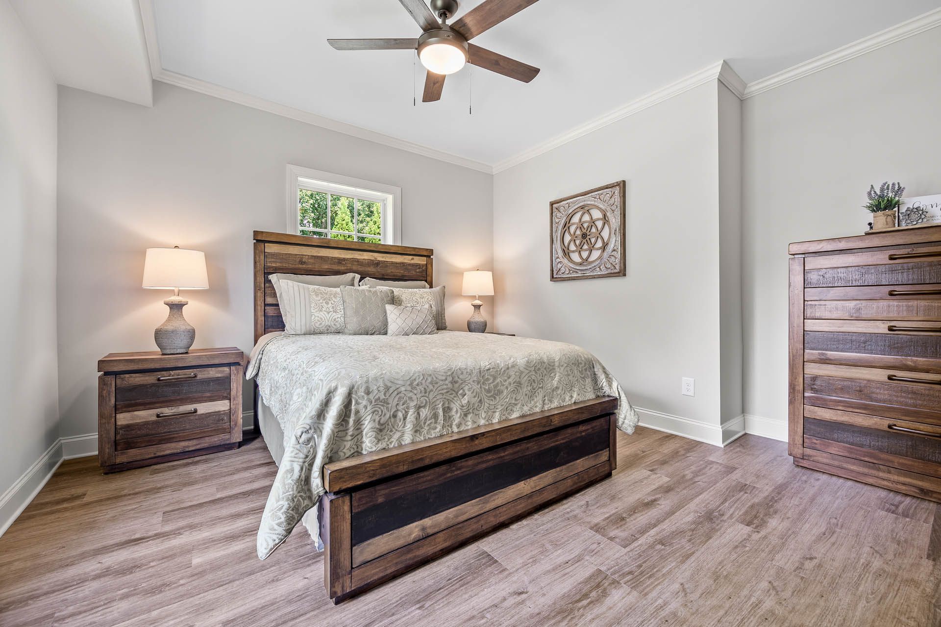 Bedroom with rustic wooden furniture, including a bed, nightstands, and dresser, with light gray walls and wood-look flooring.