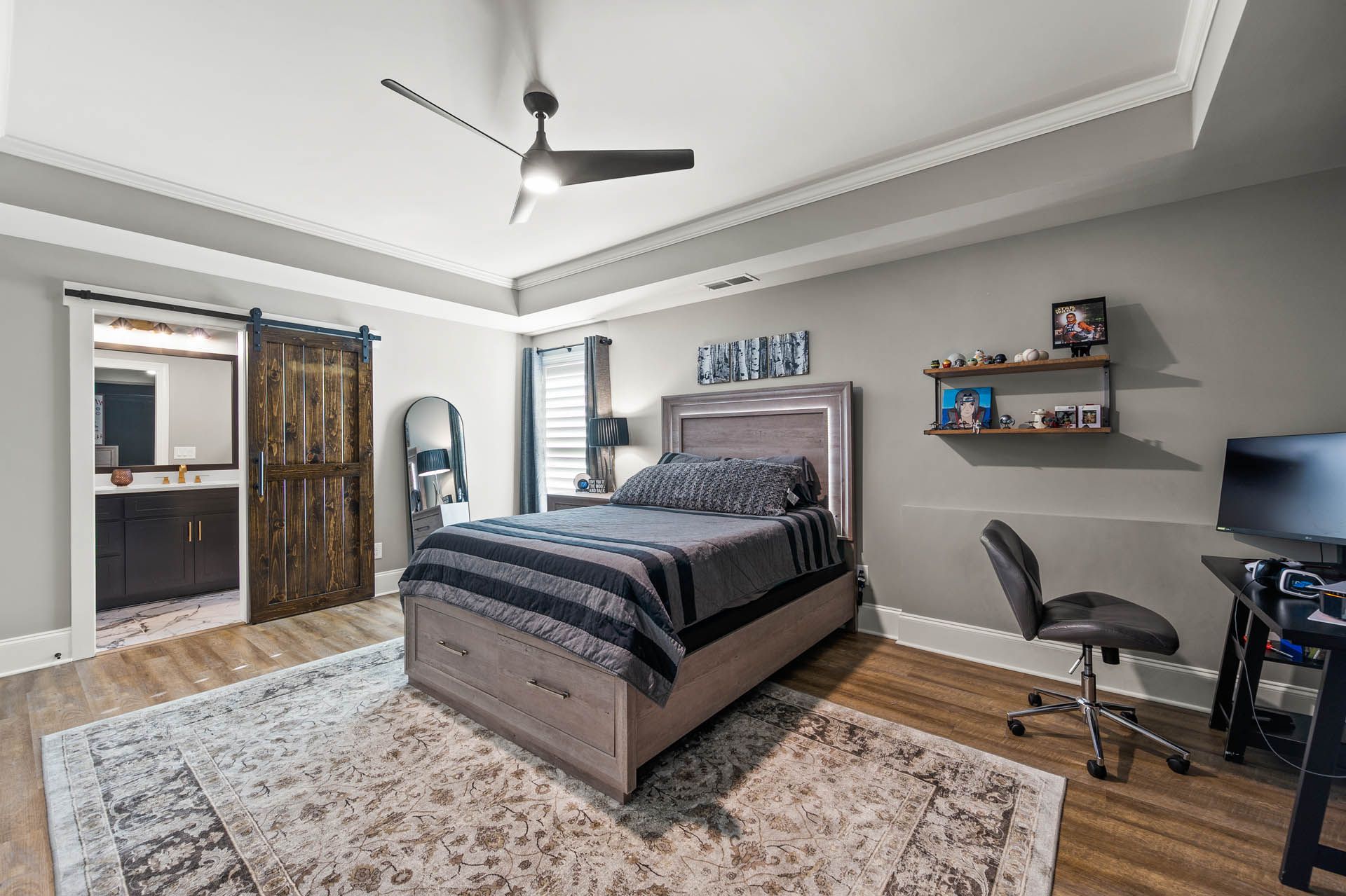 a bedroom with a bed a desk and a ceiling fan