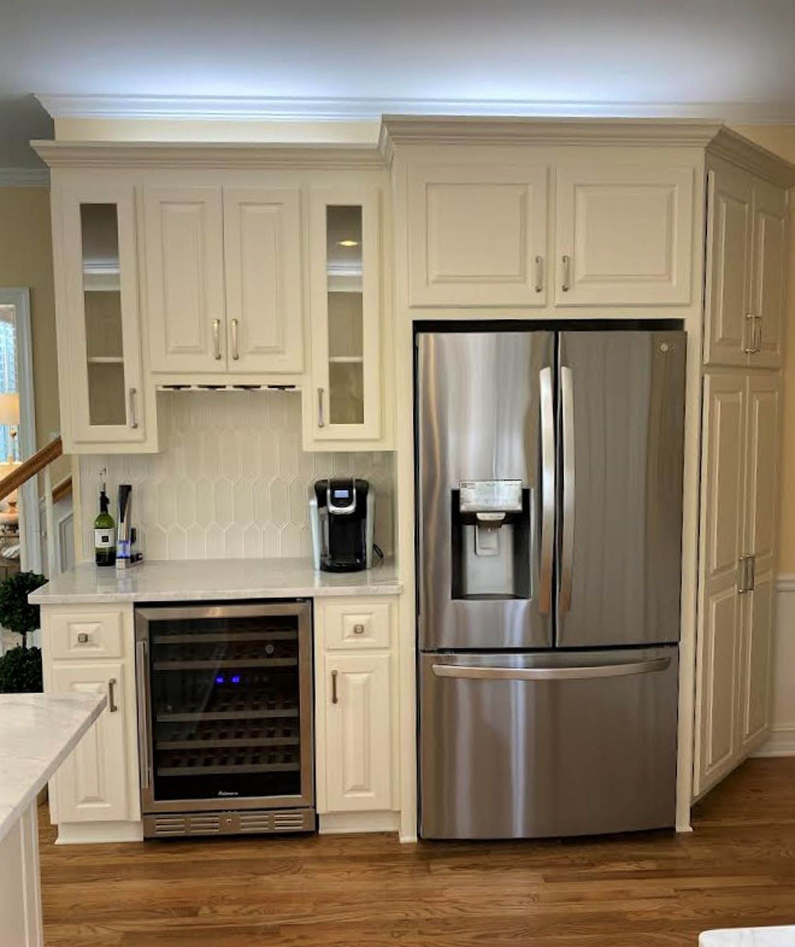 Cream-colored kitchen cabinetry with a stainless steel refrigerator and wine cooler. Includes a built-in coffee maker.
