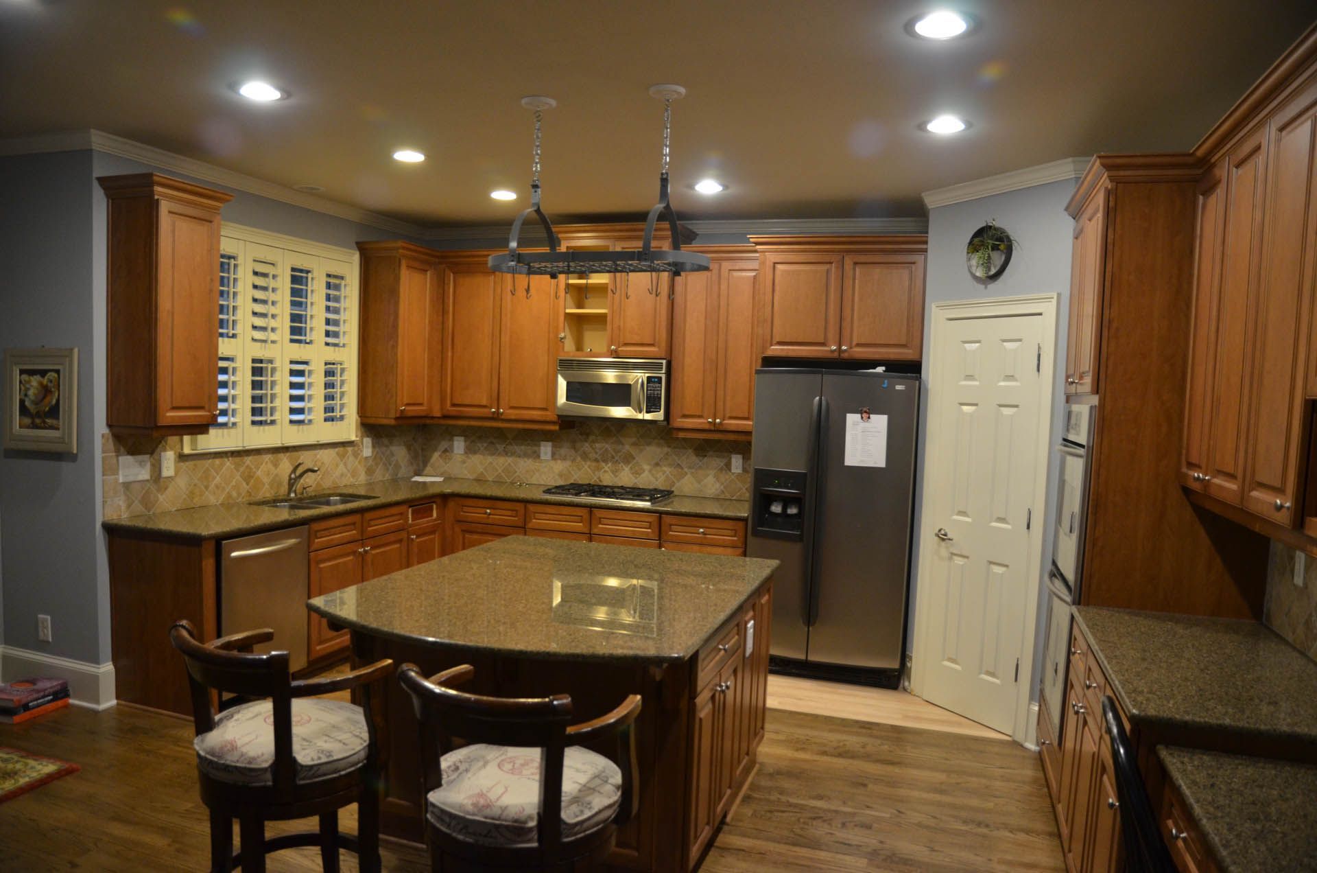 Kitchen with brown cabinets, granite countertops, stainless steel appliances, and a central island with seating.