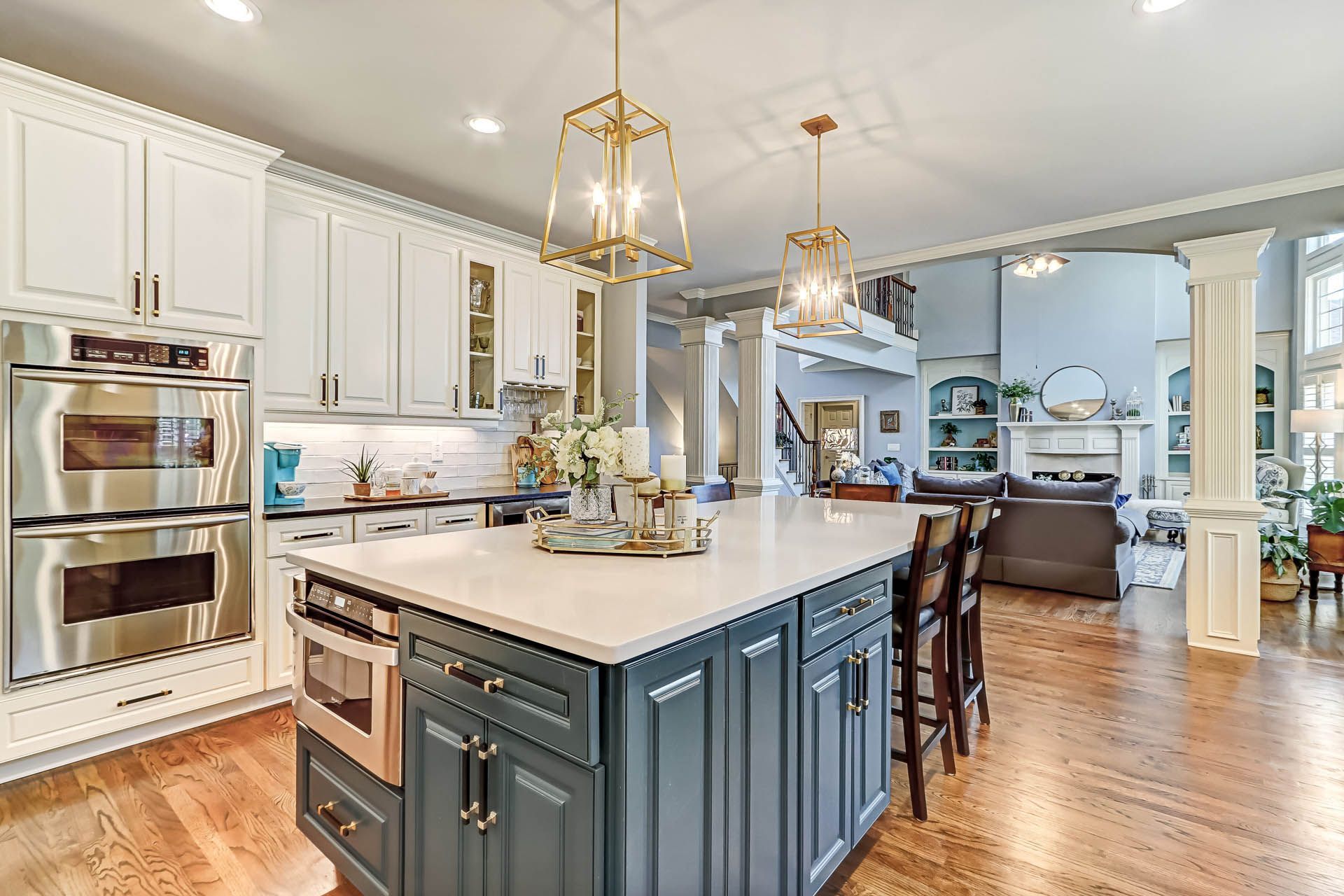 Spacious kitchen with a blue island and white cabinets, leading to a living area with a fireplace.