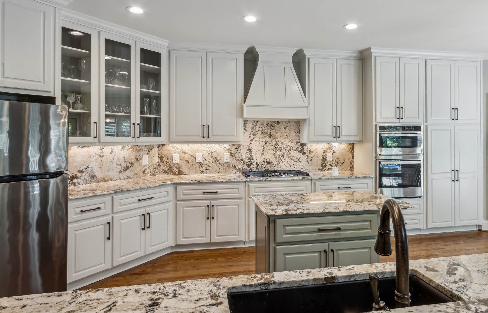 Modern kitchen with white cabinets, granite countertops, stainless steel appliances, and an island.