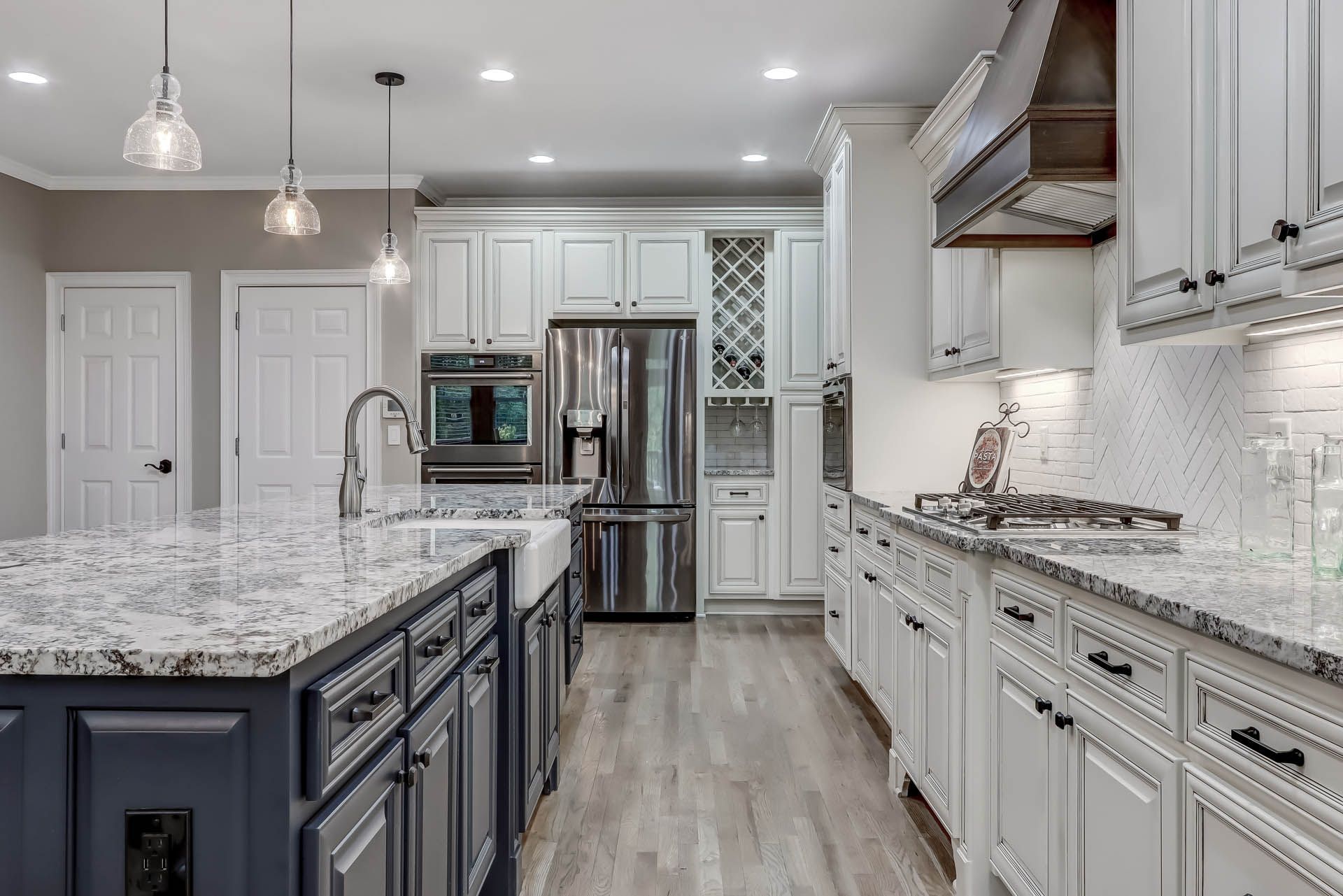 Modern kitchen with white cabinets, blue island, stainless steel appliances, and light gray flooring.