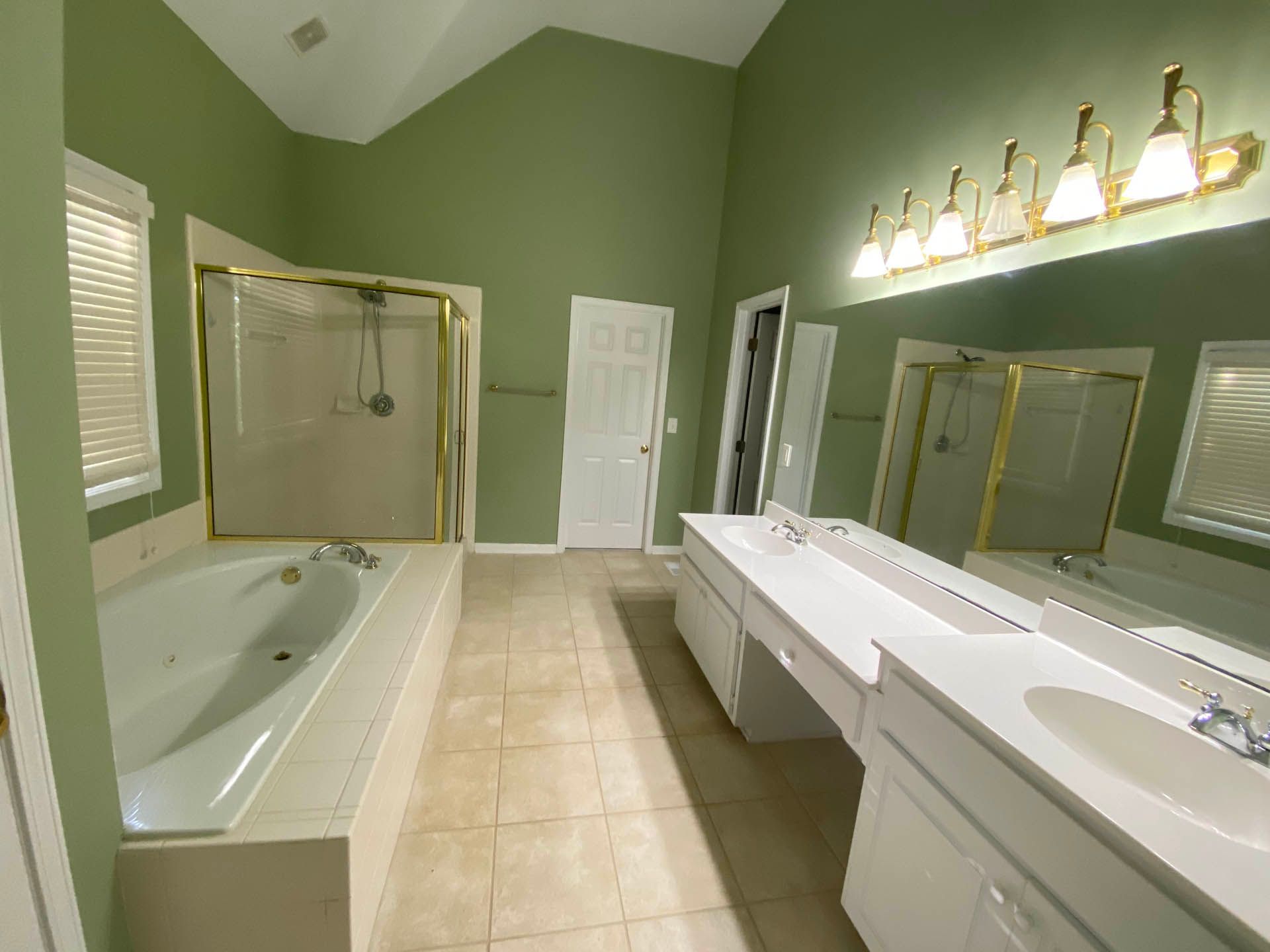 a bathroom with green walls and white cabinets