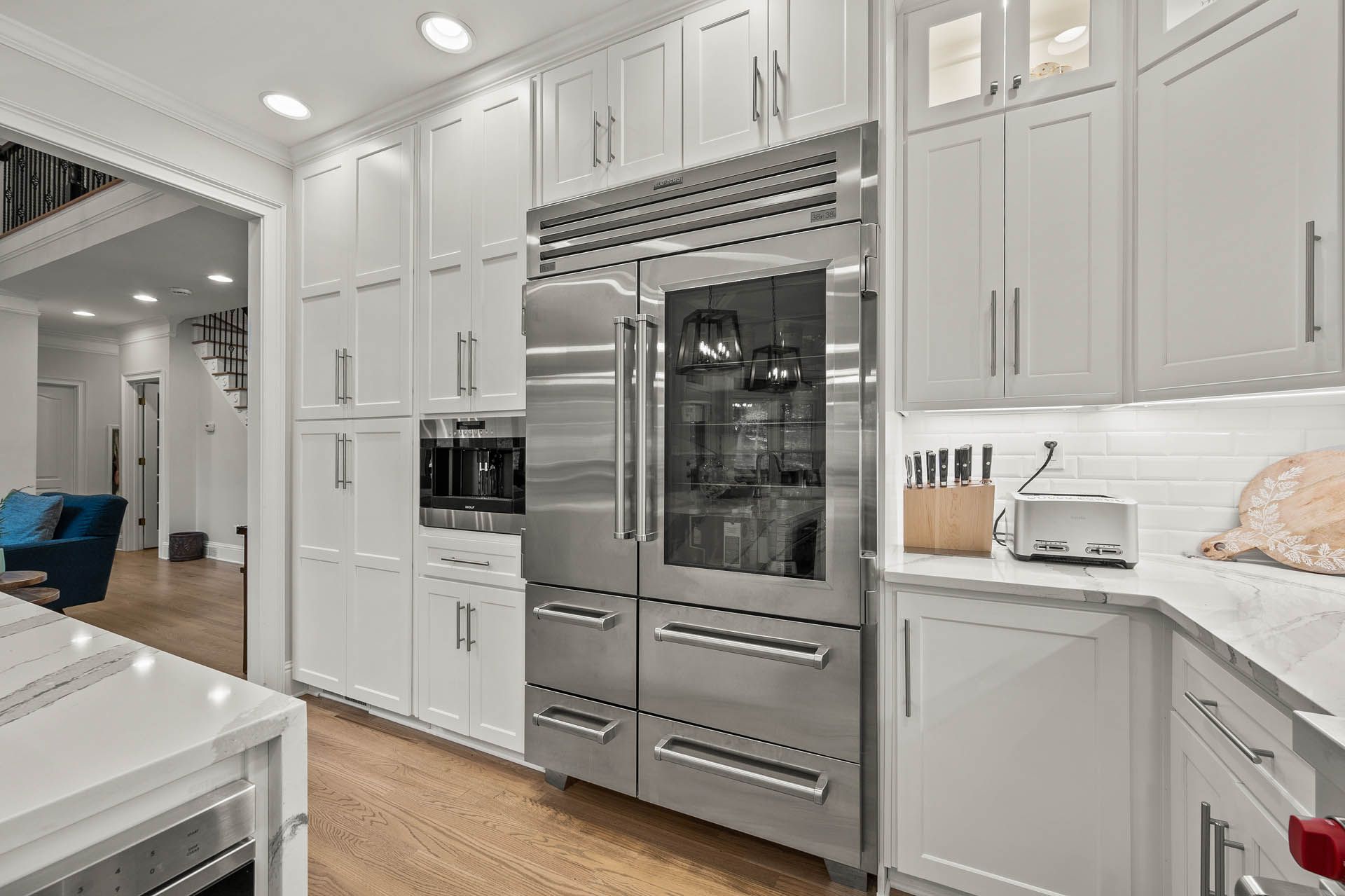 Bright, white kitchen with stainless steel refrigerator and matching cabinetry. Countertop and appliances are visible.