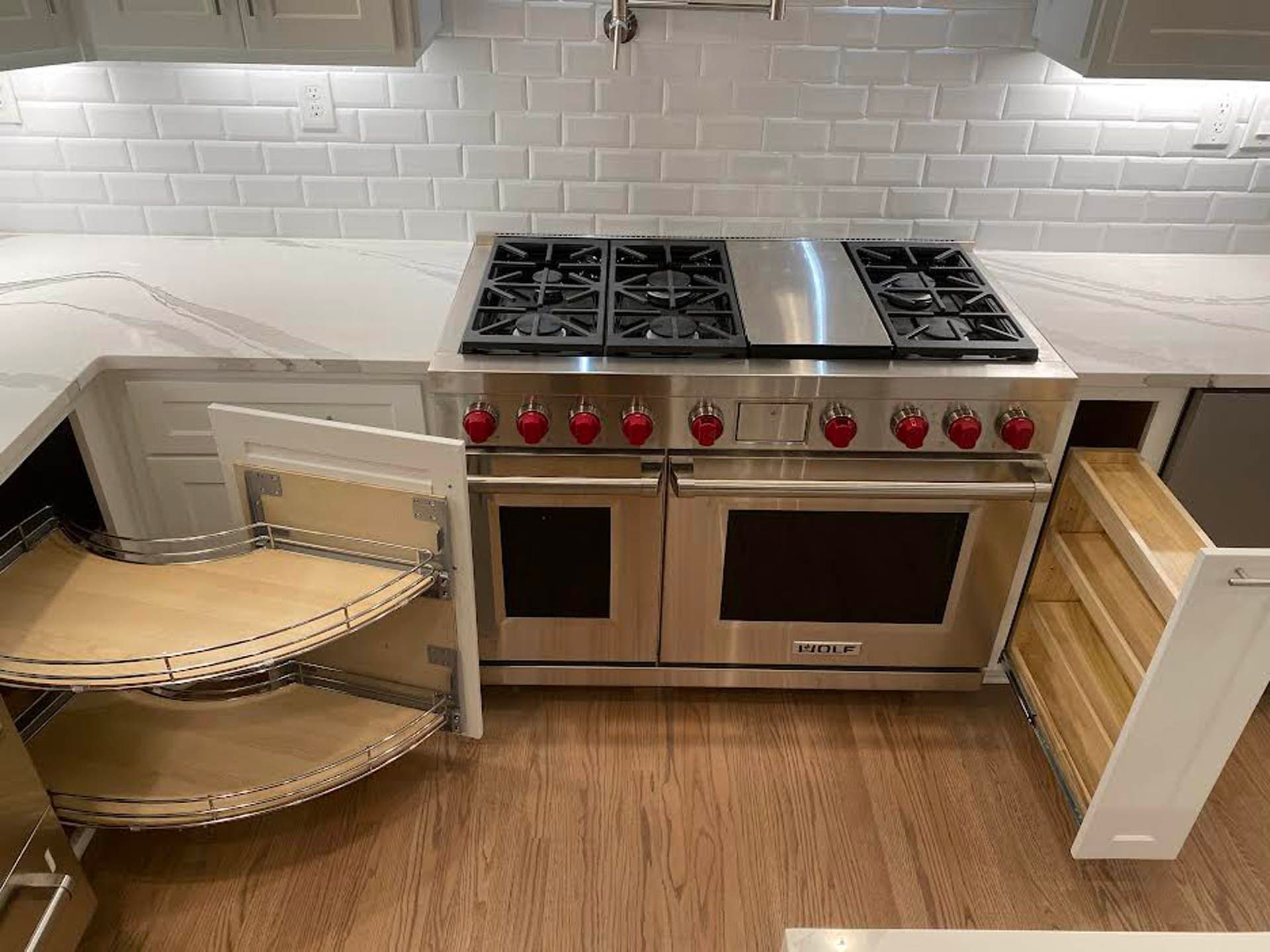Kitchen with stainless steel range and white cabinets. Features include a pull-out spice rack and a corner cabinet with pull-out shelving.