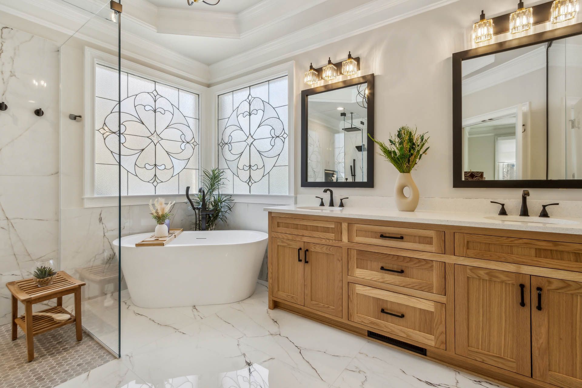 Spacious, light-filled bathroom featuring a freestanding bathtub, double vanity with oak cabinets, and marble tile floors.