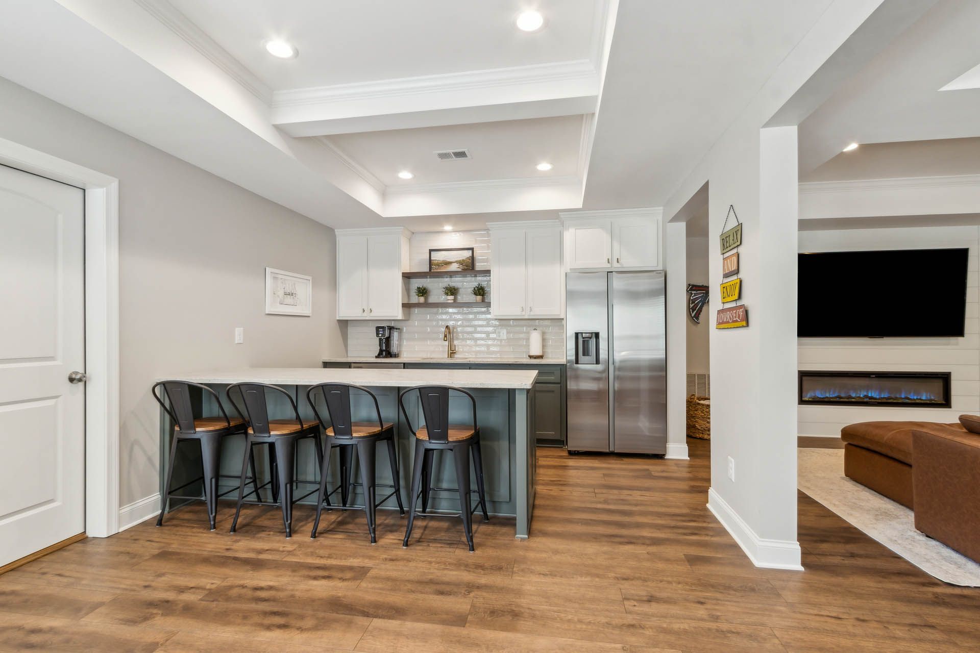 Modern kitchen and living area with a breakfast bar, stainless steel appliances, and a fireplace.