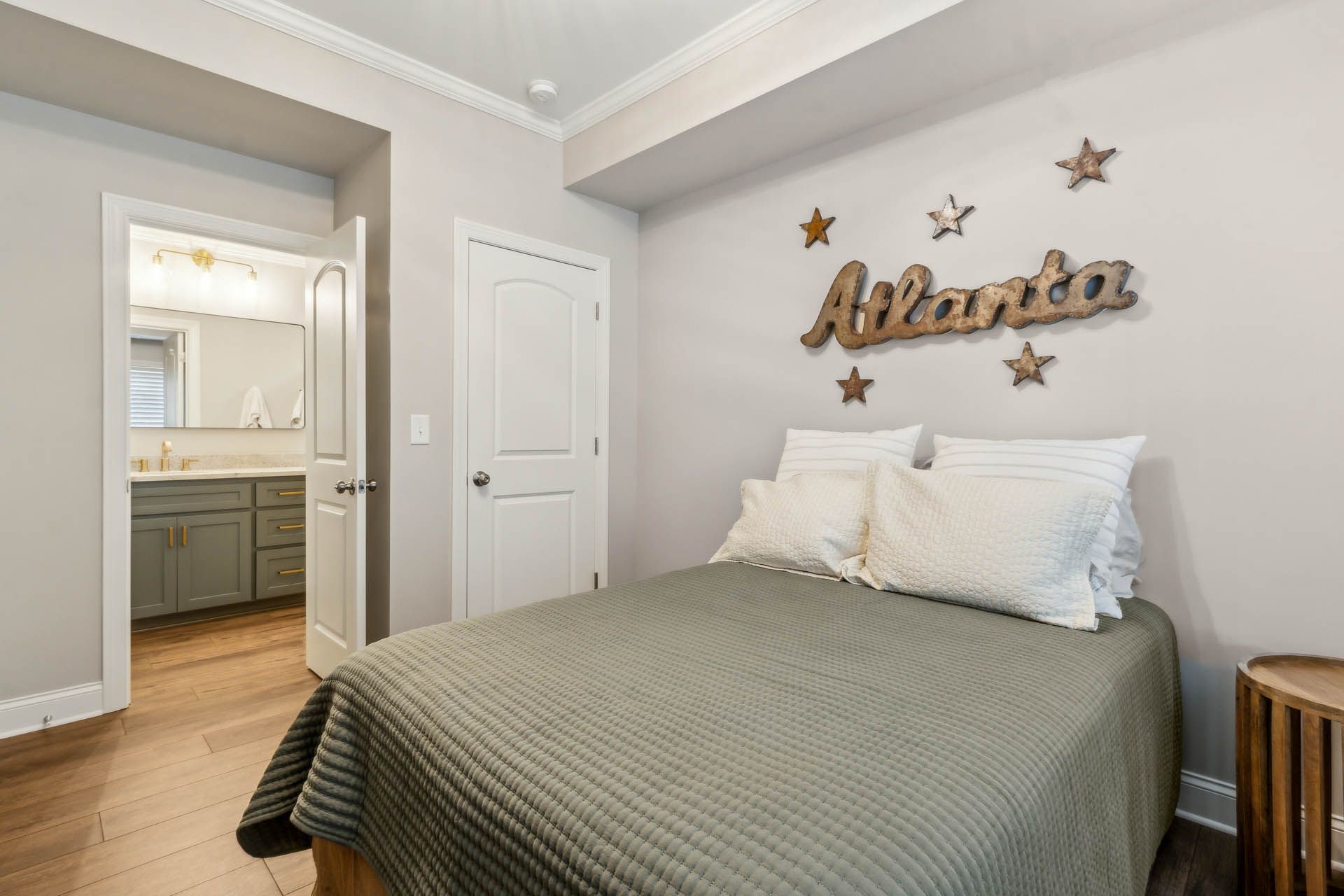 Bedroom with bed, Atlanta sign, stars, and a view of a bathroom through an open door.