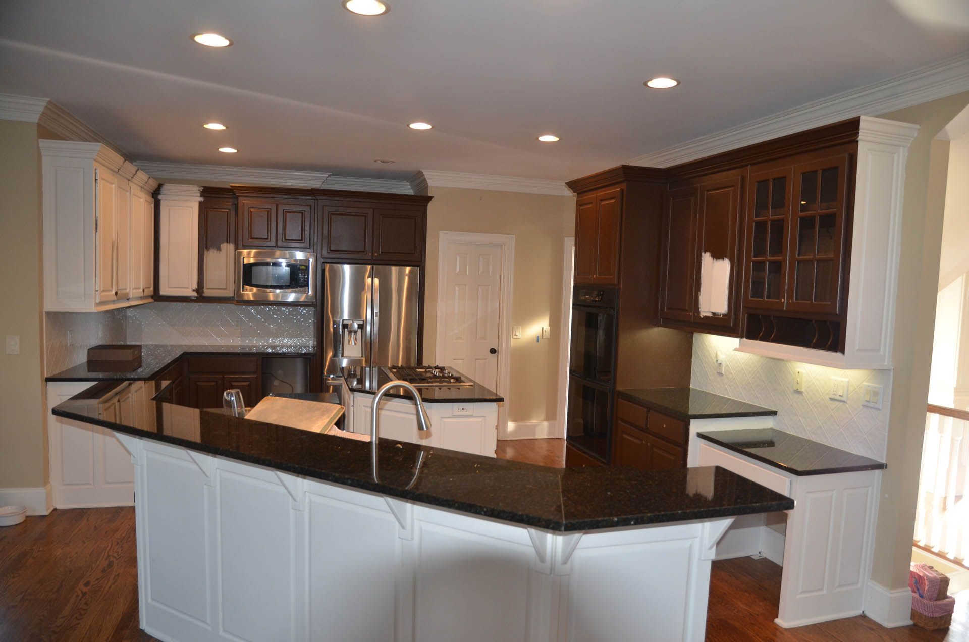Spacious kitchen with dark countertops, white and brown cabinets, and a stainless steel refrigerator.