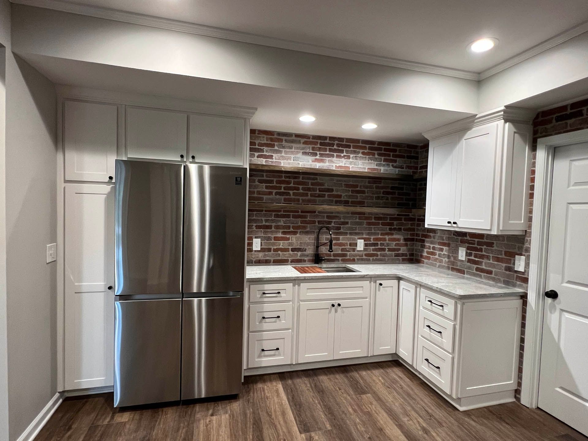 a kitchen with white cabinets and a stainless steel refrigerator