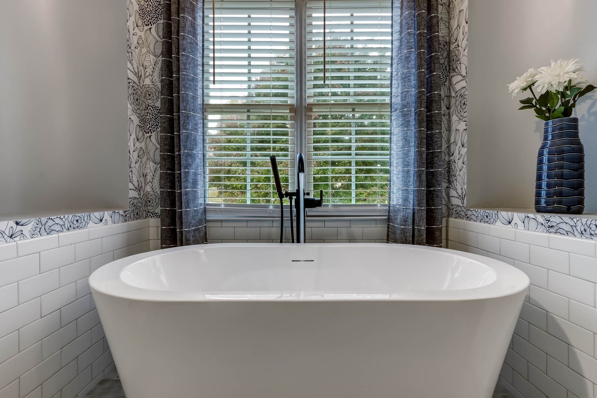 a bathtub in a bathroom next to a window with blinds