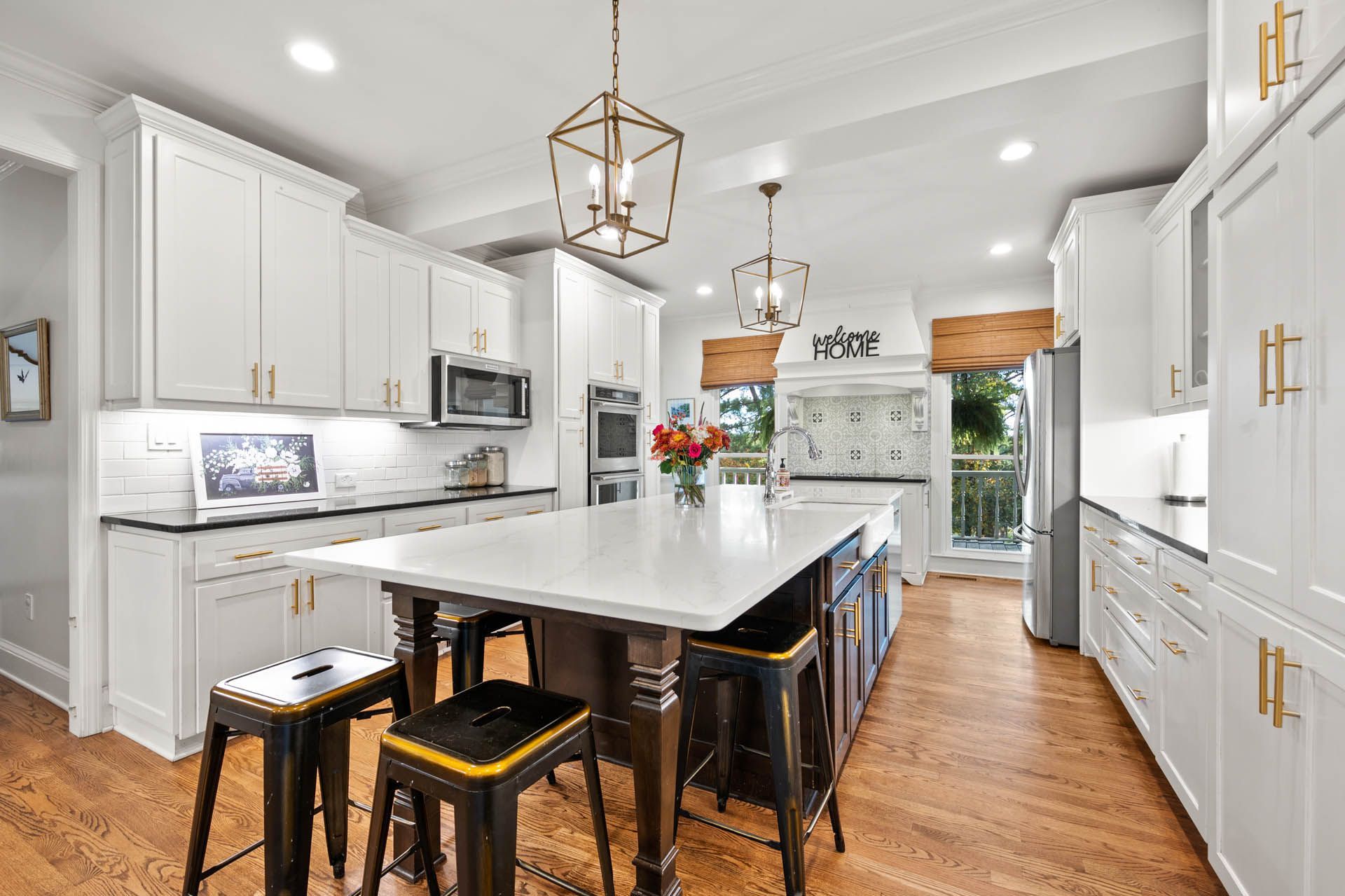 Bright kitchen with white cabinets, a large island with seating, and gold accents.