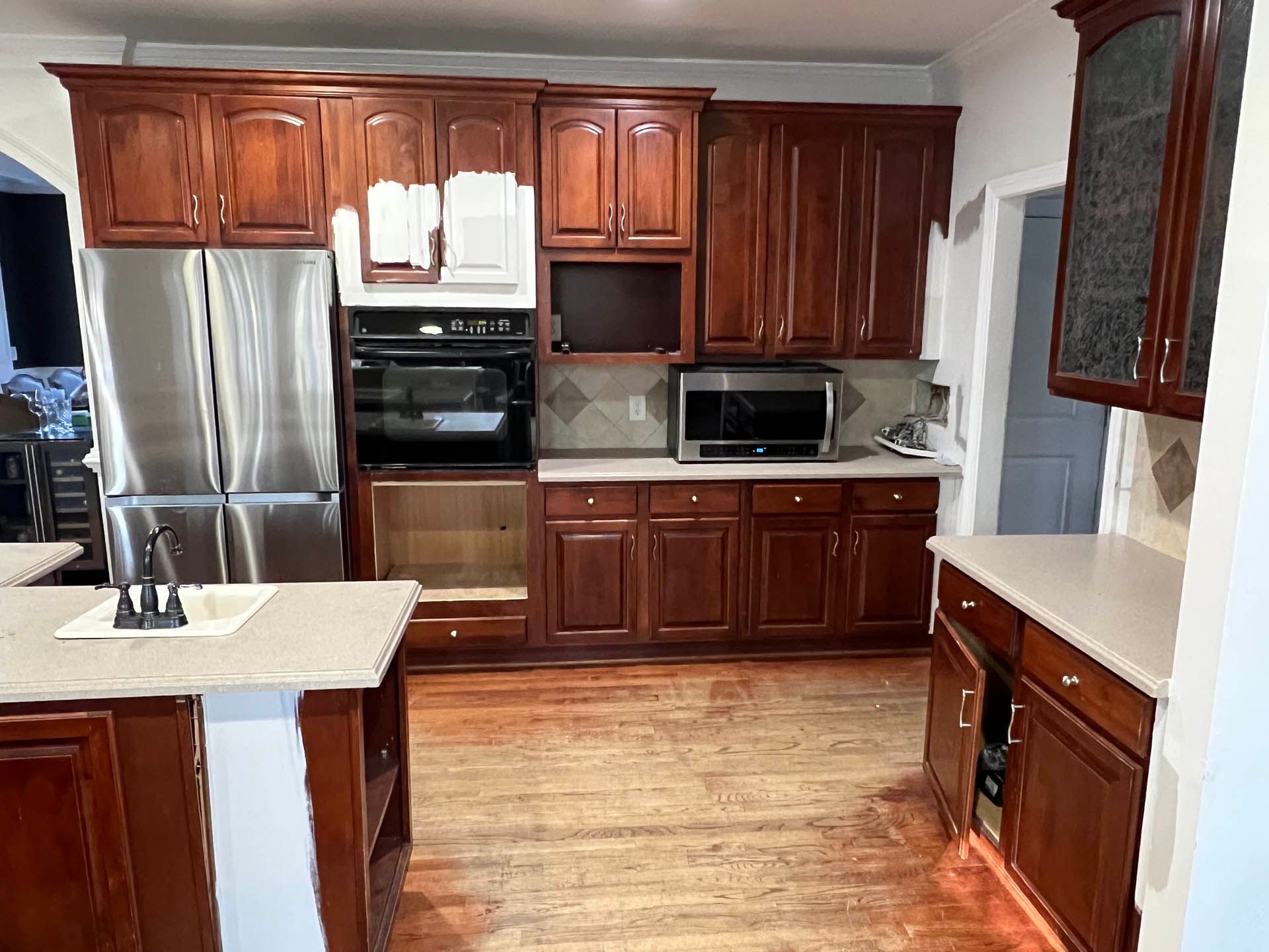 A kitchen with dark wood cabinets and stainless steel appliances. The oven door is open, revealing an empty space.