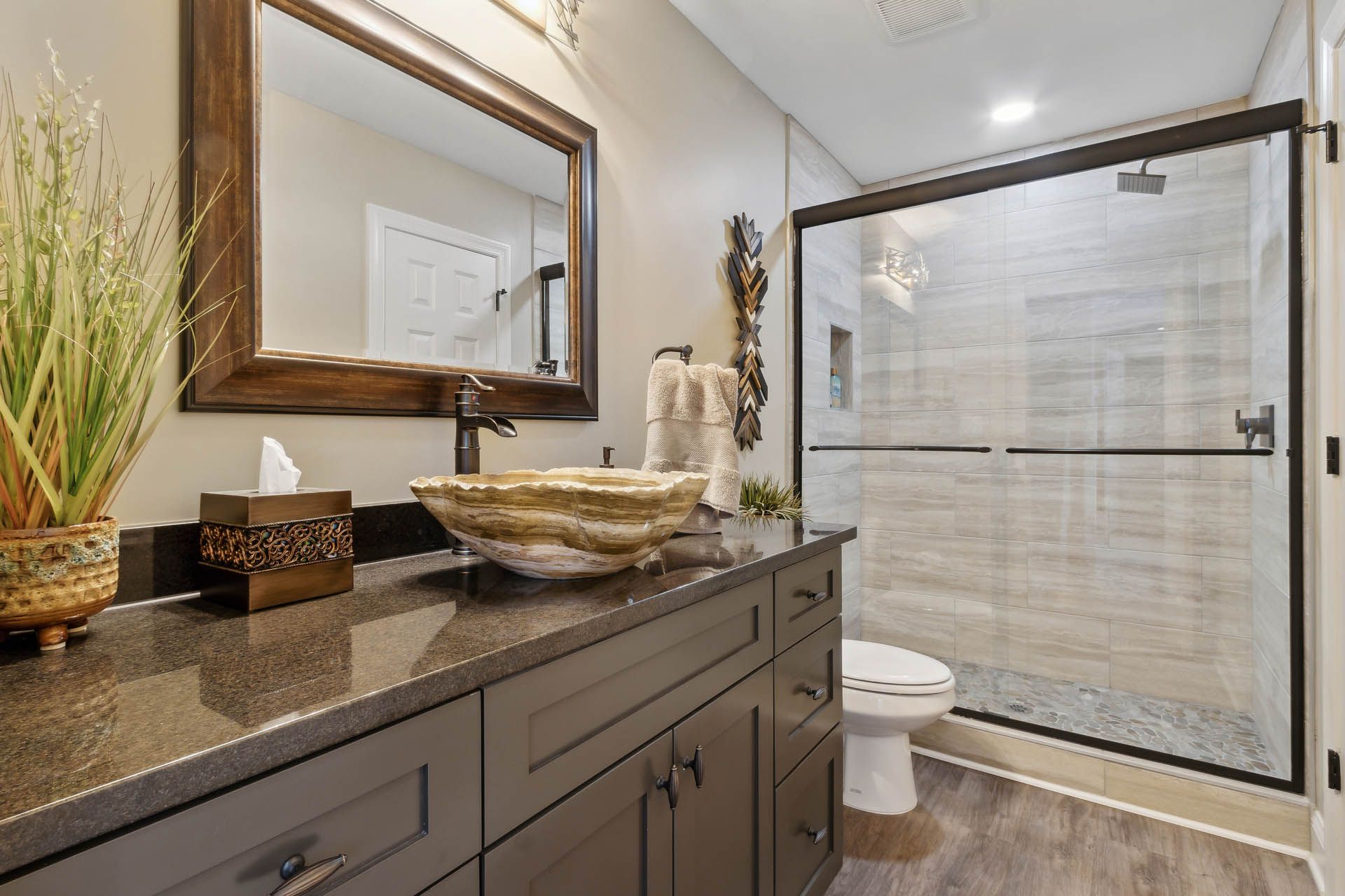 Bathroom with dark wood vanity, granite countertop, vessel sink, large mirror, glass shower, and toilet.