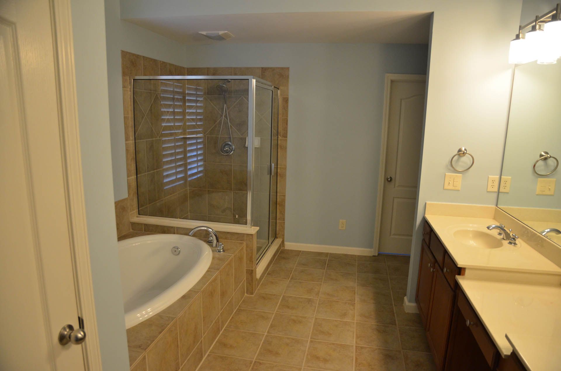 Bathroom with a soaking tub, separate shower, double vanity, and light blue walls.