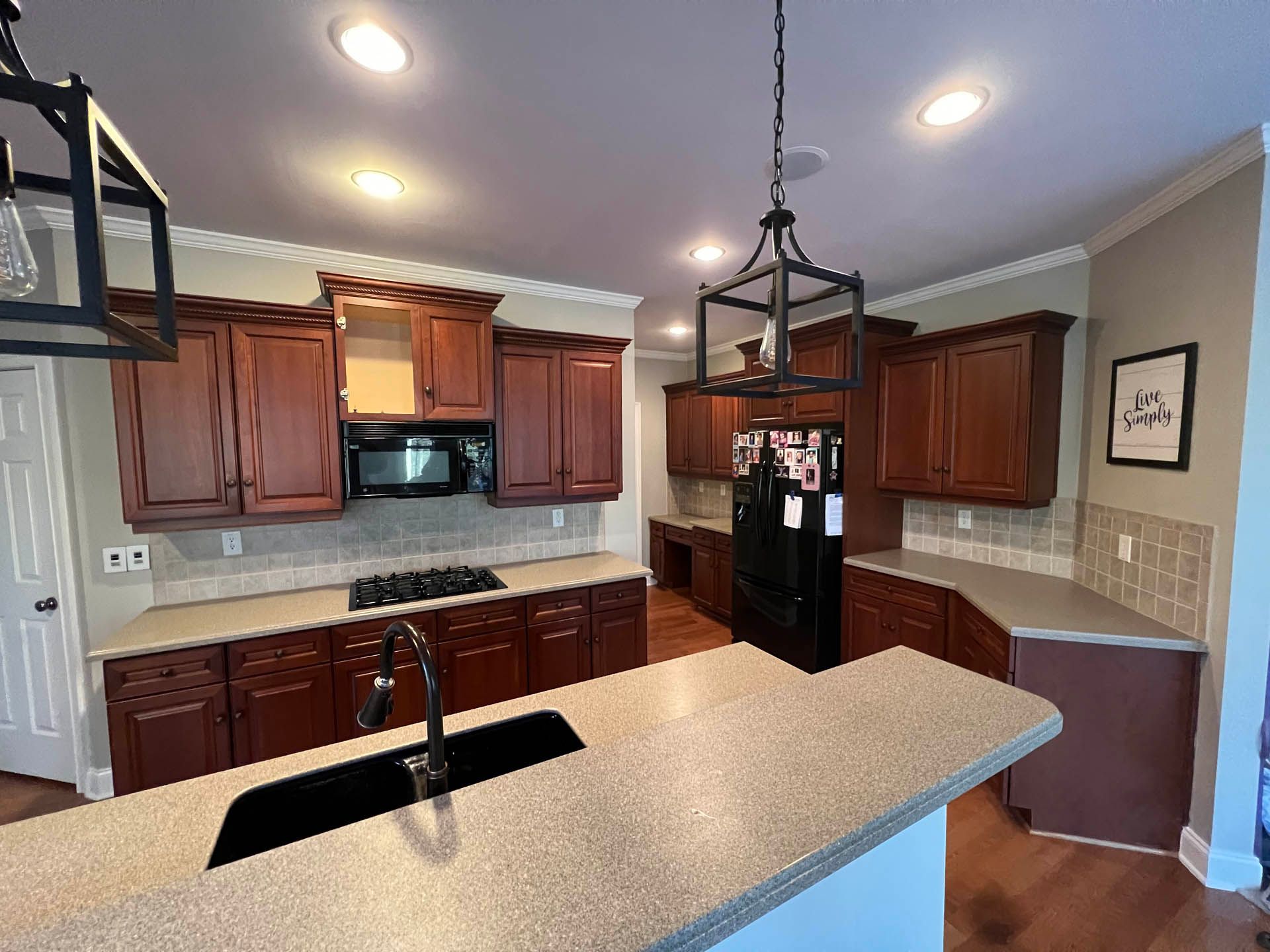 A kitchen with cherry cabinets, granite countertops, and a central island. A black stove and microwave are visible.