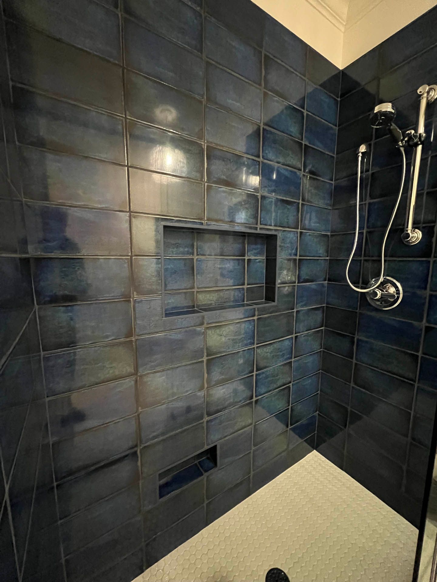 a shower with blue tiles and a white floor