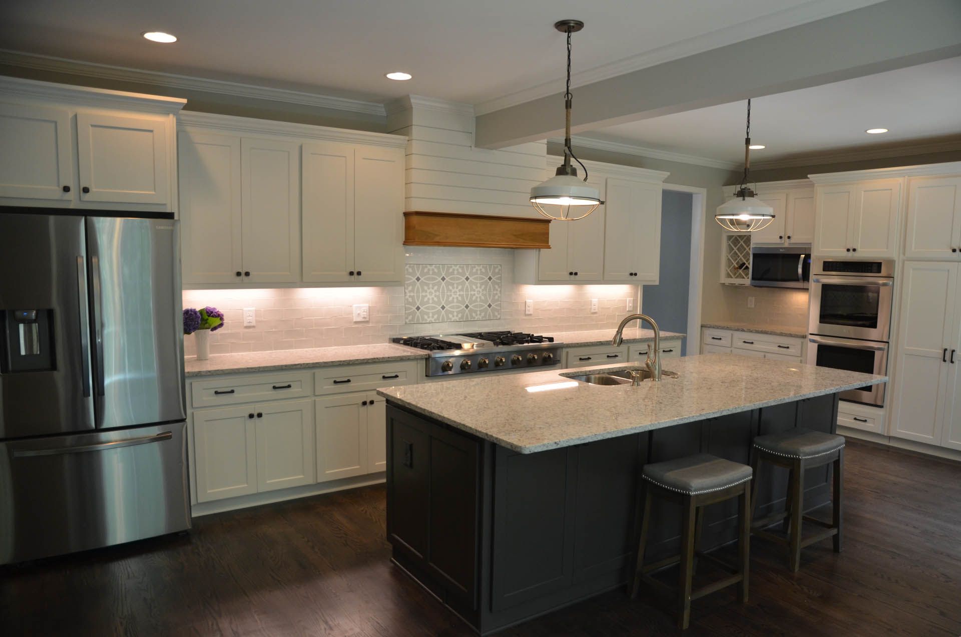 Modern kitchen with white cabinets, stainless steel appliances, and a dark gray island with seating.