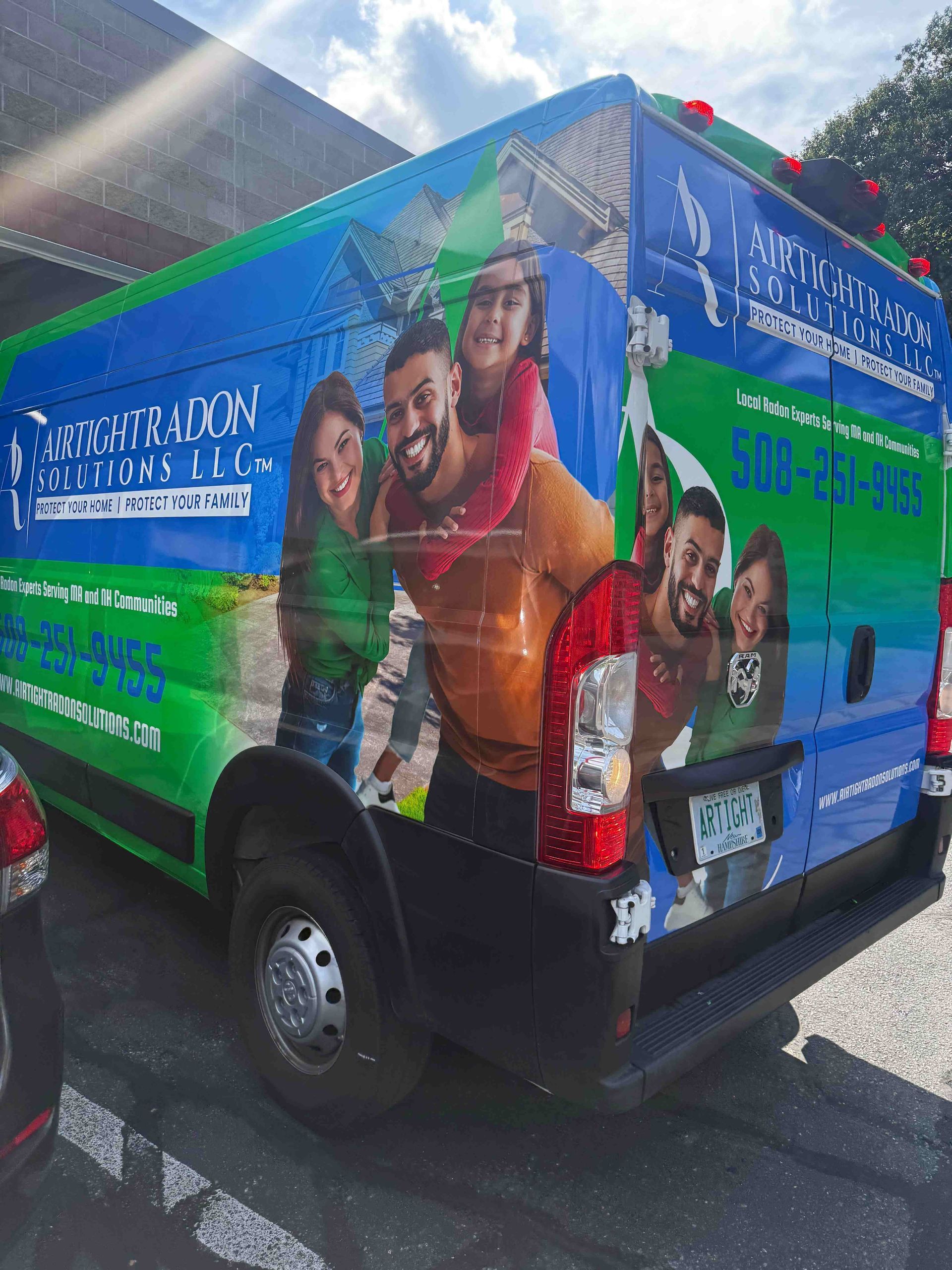 Van with family photo wrap; blue, green and white; phone number on side.