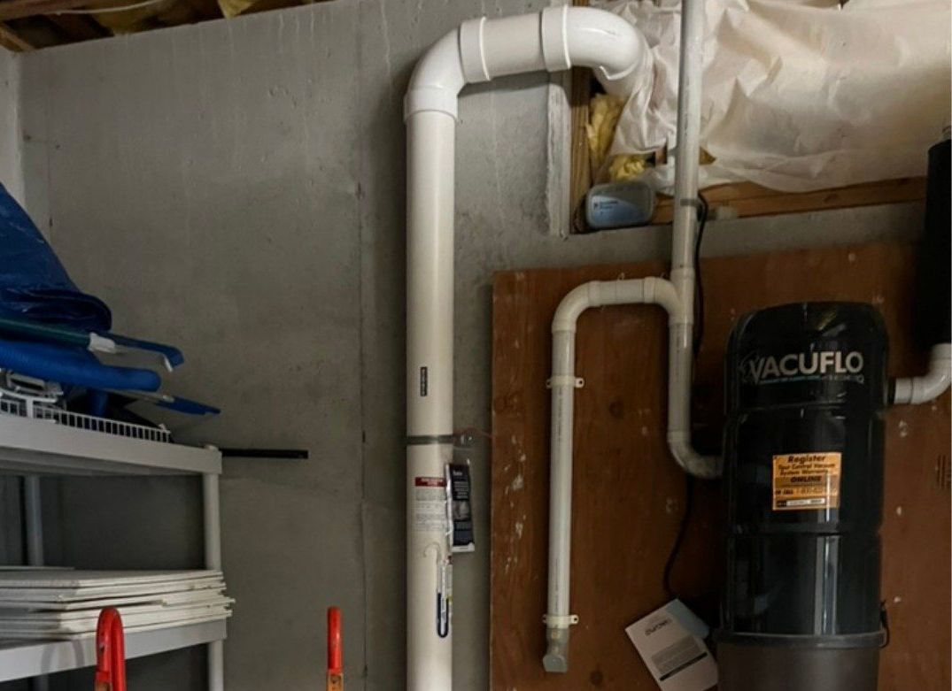 A vacuum cleaner is mounted to the wall in a garage.