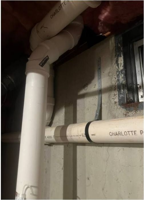 A bunch of white pipes are hanging from a wall.