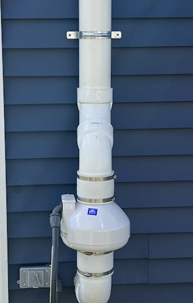 A white pipe is attached to the side of a blue house