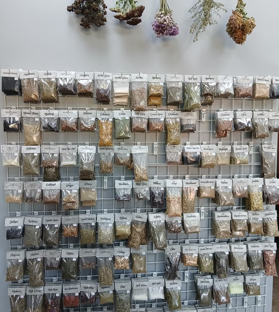 Wall display of seed packets on a grid, with dried flowers hanging above.